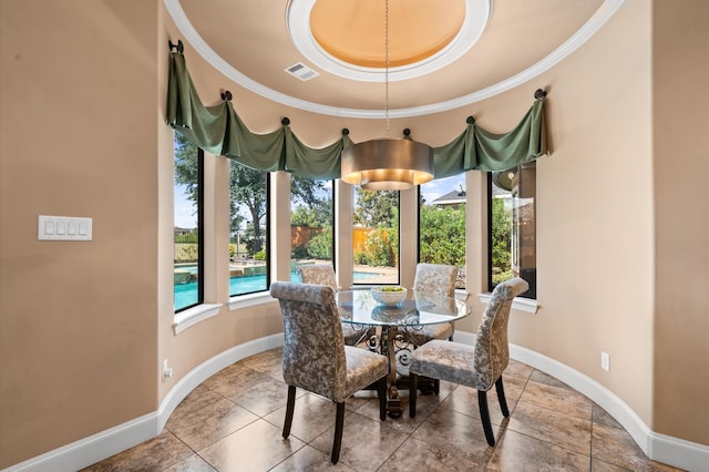 dining room with a raised ceiling and ornamental molding