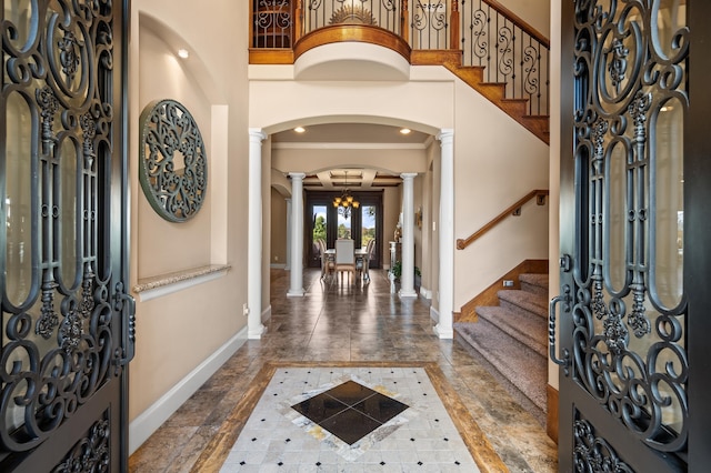 entryway featuring ornate columns, crown molding, and a chandelier