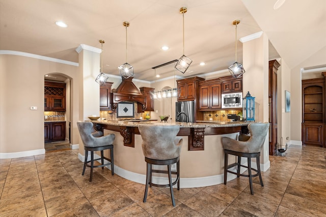 kitchen with kitchen peninsula, a breakfast bar area, appliances with stainless steel finishes, backsplash, and decorative light fixtures