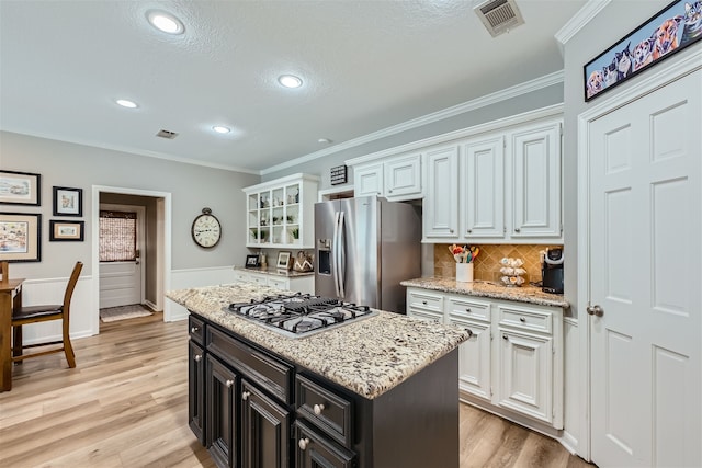 kitchen with a kitchen island, appliances with stainless steel finishes, white cabinetry, a textured ceiling, and light wood-type flooring