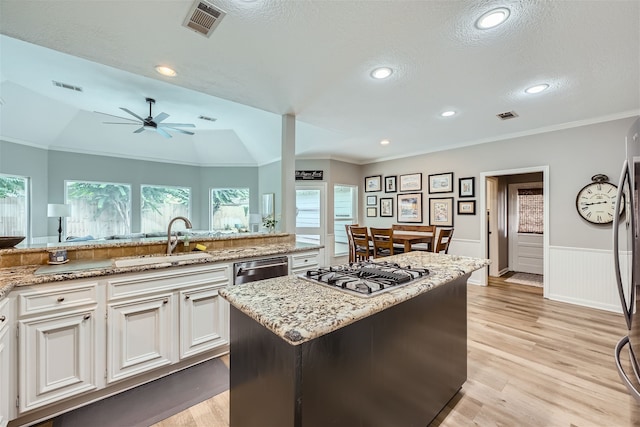 kitchen featuring lofted ceiling, white cabinets, stainless steel appliances, sink, and a center island