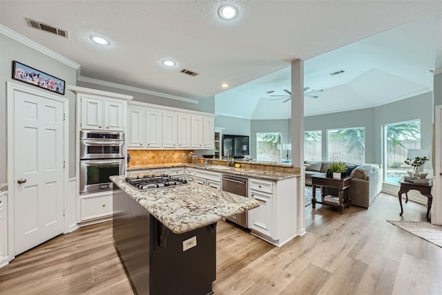 kitchen with kitchen peninsula, lofted ceiling, ceiling fan, appliances with stainless steel finishes, and white cabinetry