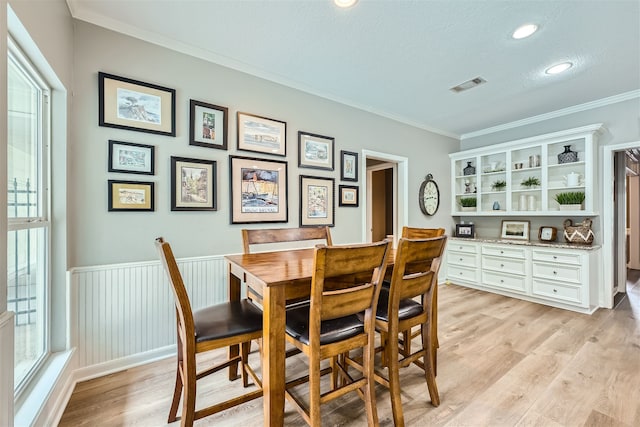 dining area with crown molding, light wood-type flooring, and a wealth of natural light