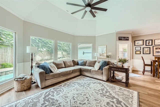 living room with a towering ceiling, hardwood / wood-style flooring, ceiling fan, and a wealth of natural light