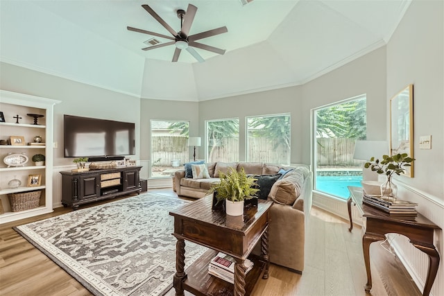 living room featuring ceiling fan, a high ceiling, light wood-type flooring, and built in shelves