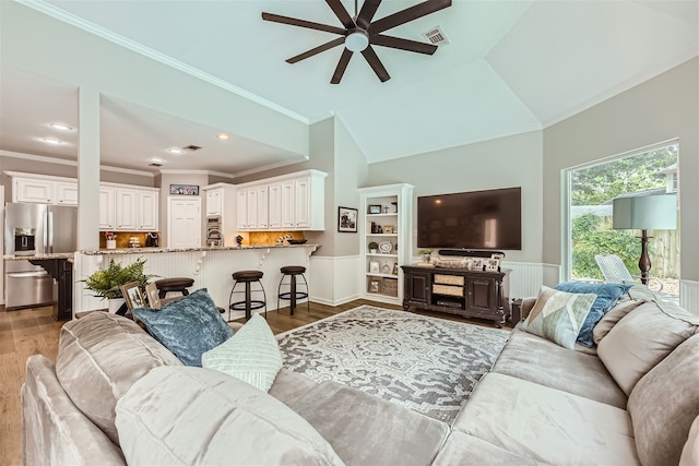 living room featuring ornamental molding, vaulted ceiling, light wood-type flooring, and ceiling fan