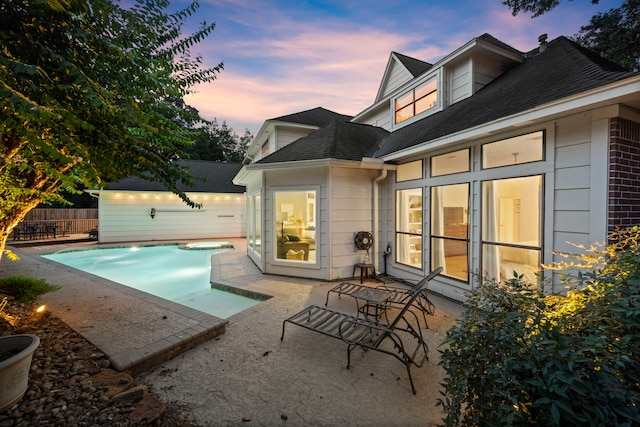 pool at dusk featuring a patio and a jacuzzi