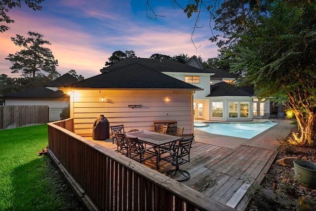 back house at dusk featuring a swimming pool side deck and a yard