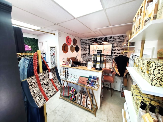 interior space featuring a drop ceiling and brick wall