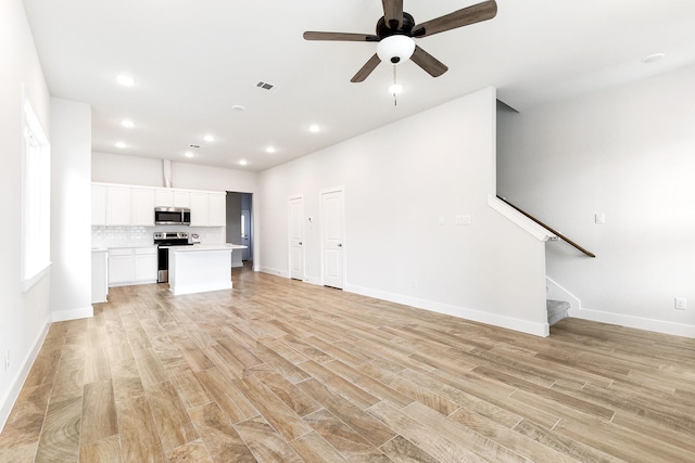 unfurnished living room with light wood-style floors, stairway, a ceiling fan, and recessed lighting