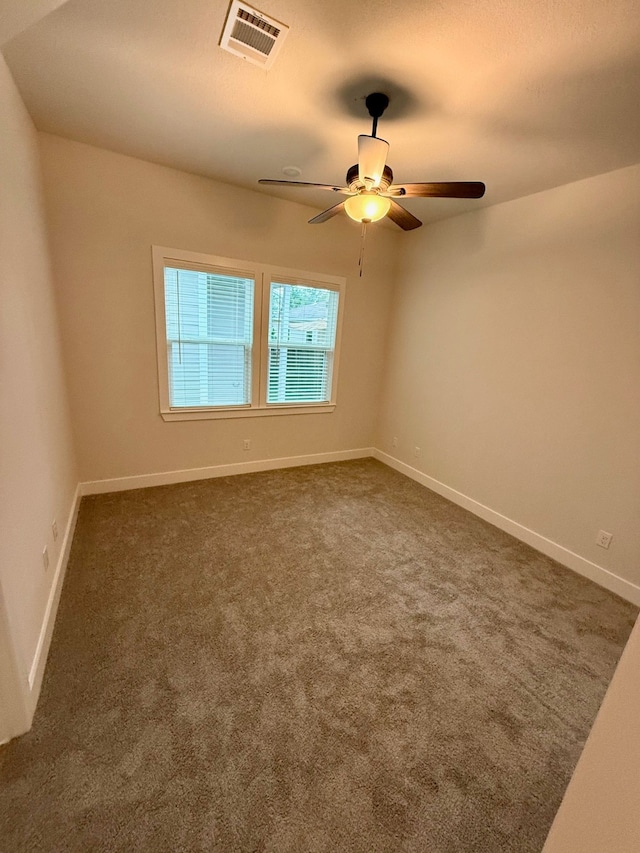 unfurnished room with dark colored carpet and ceiling fan