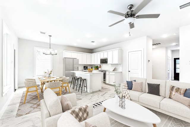 living room with ceiling fan with notable chandelier