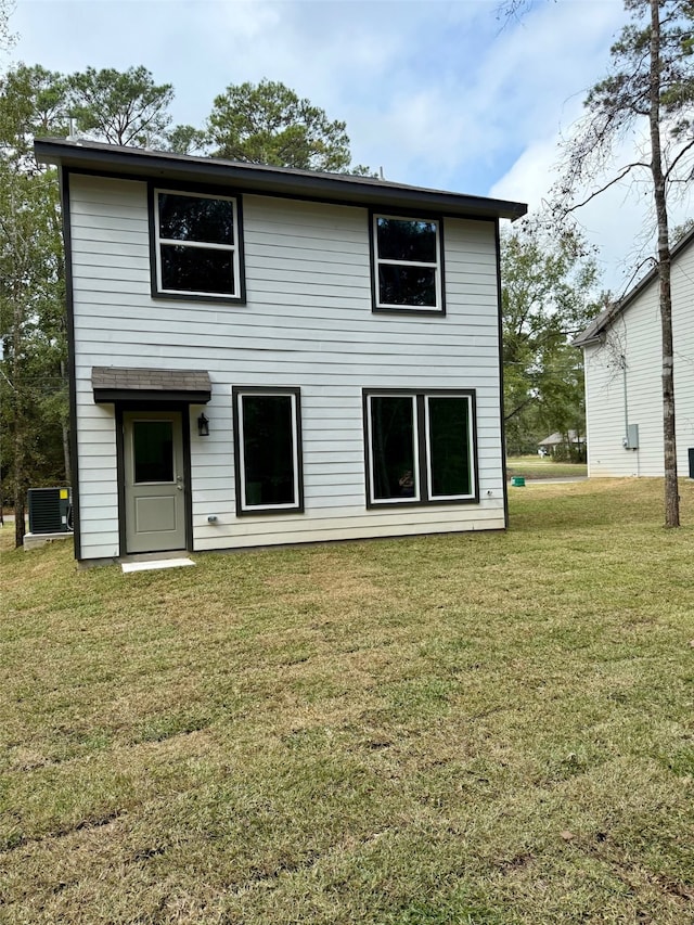 back of house with central air condition unit and a yard