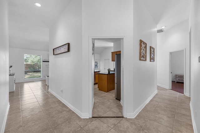 hallway with light tile patterned floors and a high ceiling