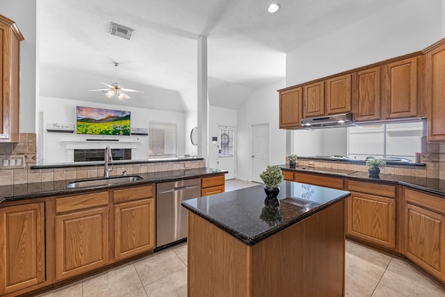 kitchen with lofted ceiling, a kitchen island, stainless steel dishwasher, dark stone countertops, and sink