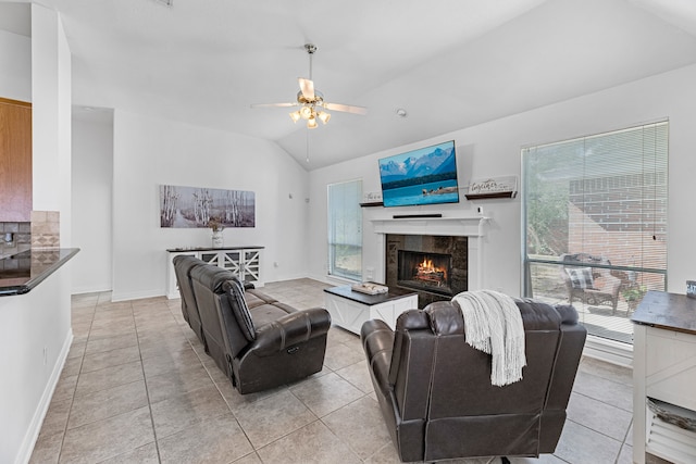 living room featuring ceiling fan, light tile patterned floors, a tile fireplace, and vaulted ceiling