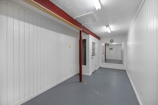 basement featuring a textured ceiling and wooden walls