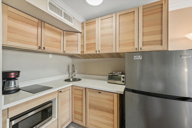 kitchen featuring light brown cabinets, sink, ornamental molding, and stainless steel appliances