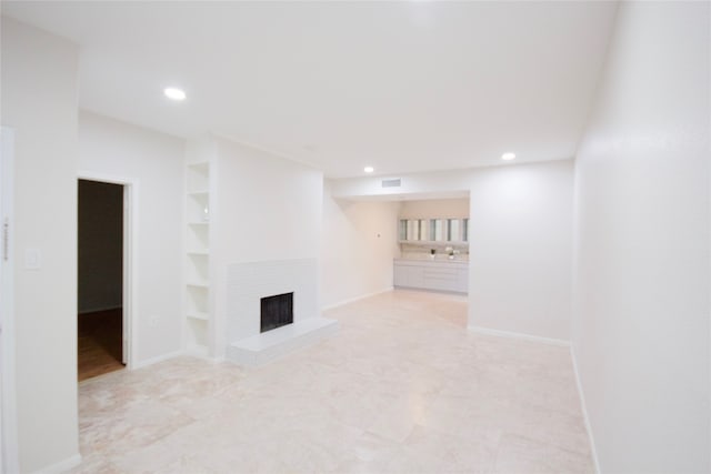 unfurnished living room featuring a fireplace and built in shelves