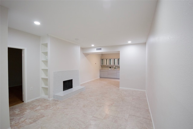 unfurnished living room featuring built in shelves and a brick fireplace