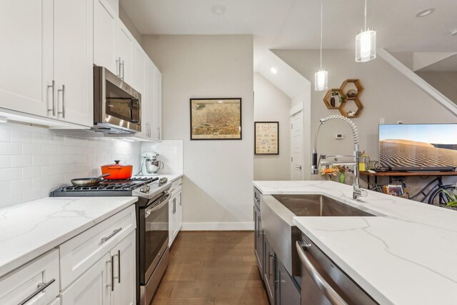 kitchen featuring stainless steel appliances, white cabinetry, hanging light fixtures, and light stone countertops