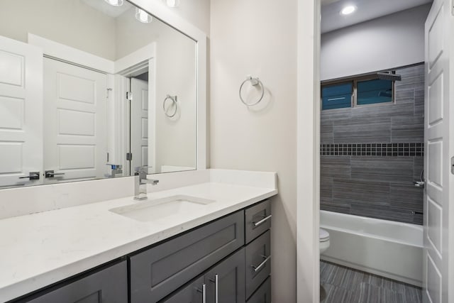 full bathroom featuring toilet, tiled shower / bath, and vanity