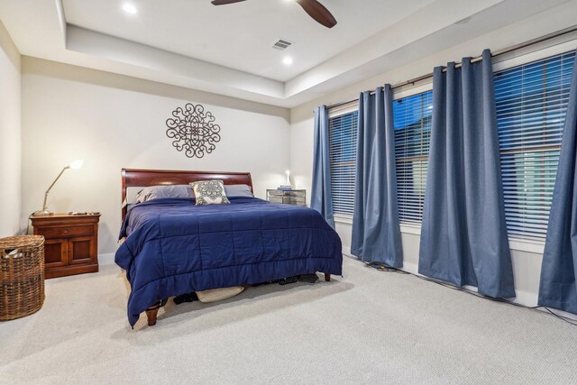 carpeted bedroom featuring ceiling fan and a raised ceiling