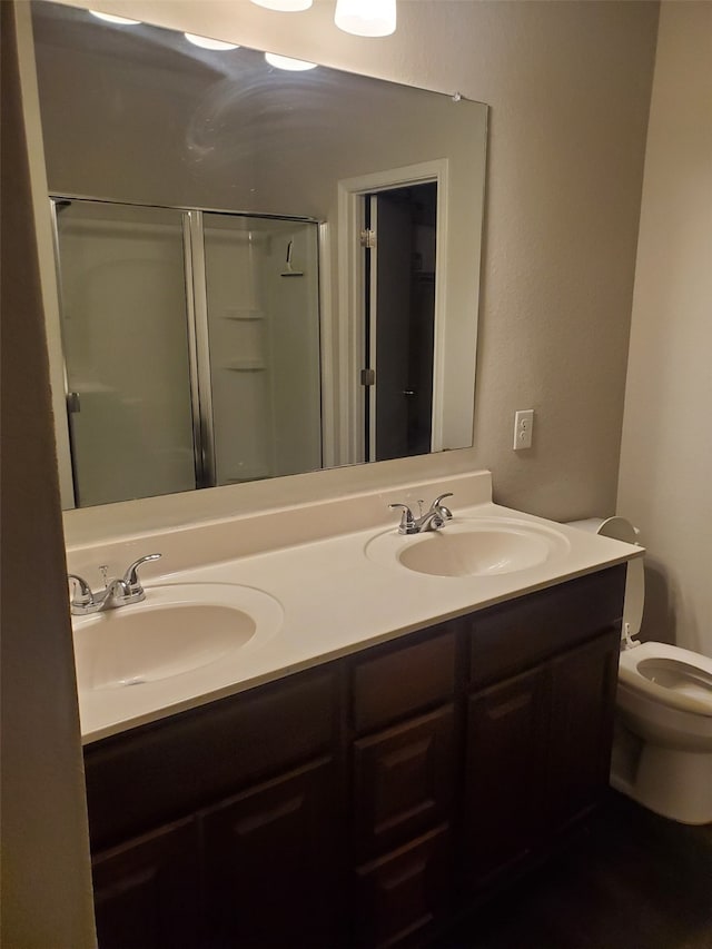 bathroom with a shower with door, vanity, and toilet