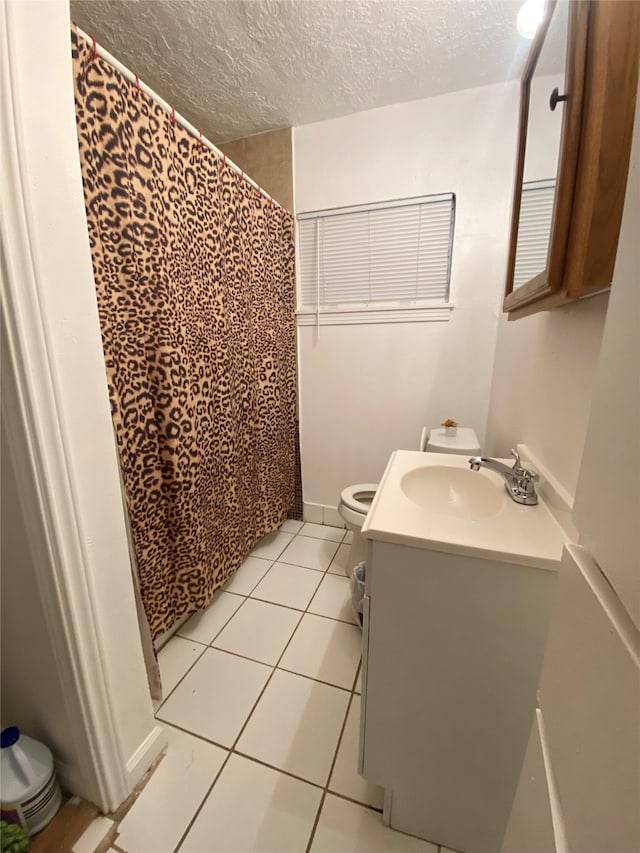 bathroom featuring tile patterned floors, toilet, vanity, a textured ceiling, and walk in shower