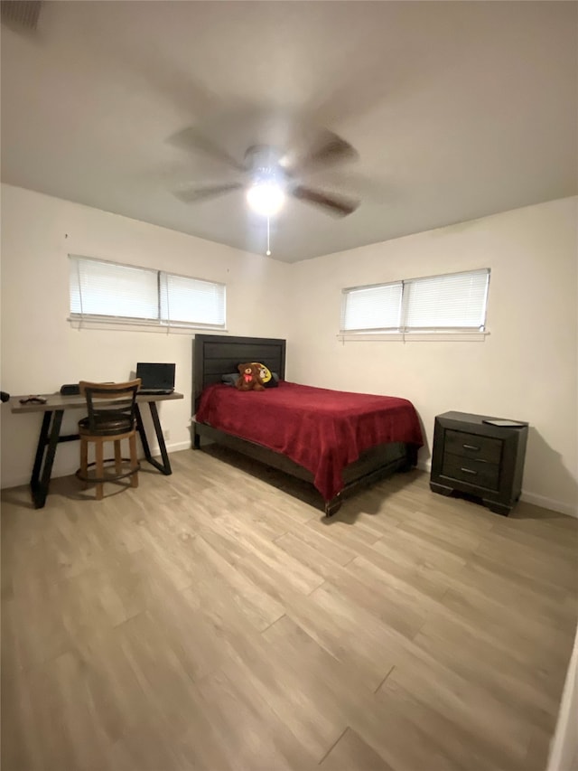 bedroom featuring ceiling fan, multiple windows, and light hardwood / wood-style flooring