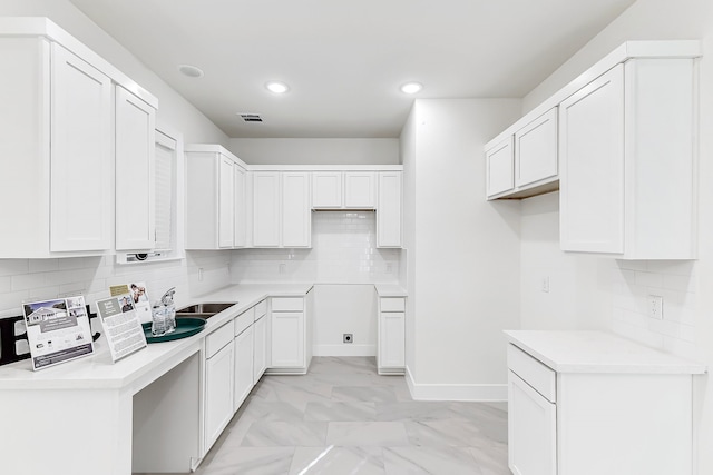 kitchen with decorative backsplash, white cabinetry, and sink