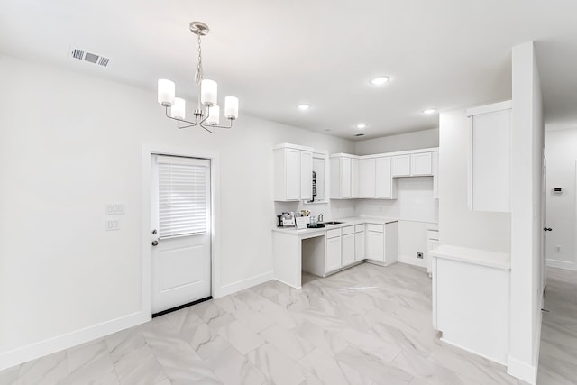 kitchen with white cabinets, a notable chandelier, pendant lighting, and sink