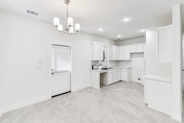 kitchen with a chandelier, white cabinetry, sink, and hanging light fixtures