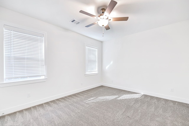 empty room with carpet flooring, a wealth of natural light, and ceiling fan