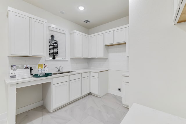 kitchen featuring backsplash, white cabinetry, and sink