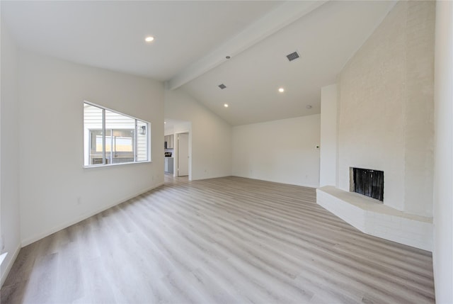 unfurnished living room featuring light wood-type flooring, a brick fireplace, and vaulted ceiling with beams