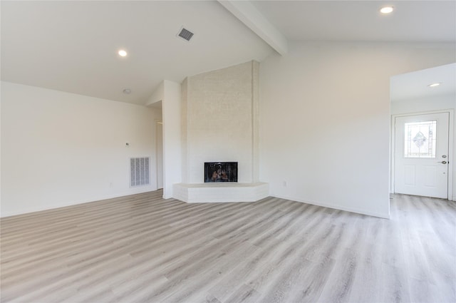 unfurnished living room with vaulted ceiling with beams, a fireplace, and light wood-type flooring