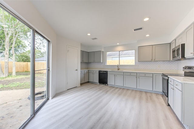 kitchen featuring tasteful backsplash, gray cabinets, and appliances with stainless steel finishes