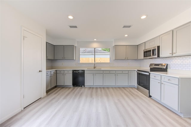 kitchen with stainless steel appliances, sink, gray cabinetry, and light wood-type flooring