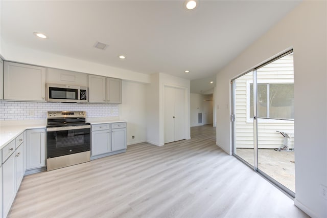 kitchen featuring gray cabinets, tasteful backsplash, appliances with stainless steel finishes, and light hardwood / wood-style flooring