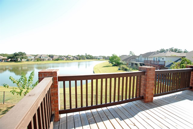 wooden terrace featuring a water view and a lawn