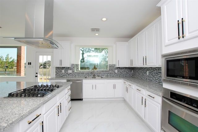 kitchen with island exhaust hood, white cabinets, stainless steel appliances, and plenty of natural light