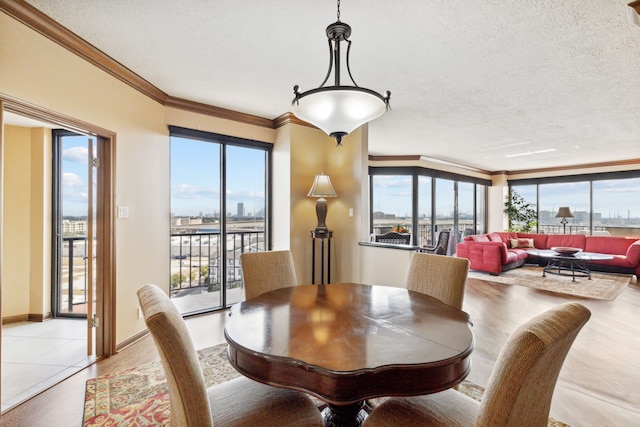 dining room featuring ornamental molding, a textured ceiling, and light wood-type flooring