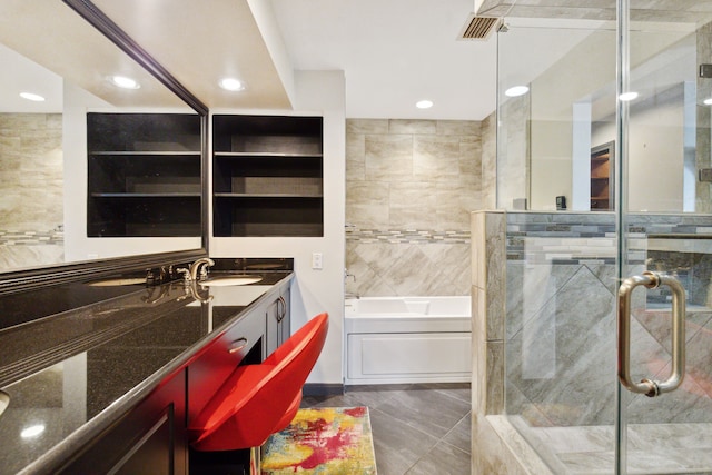 bathroom with vanity, independent shower and bath, tile patterned floors, and tile walls