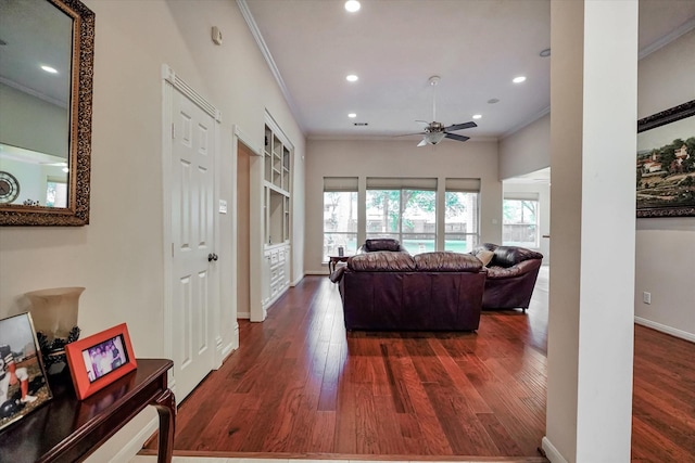 living room with dark wood-type flooring, crown molding, and ceiling fan