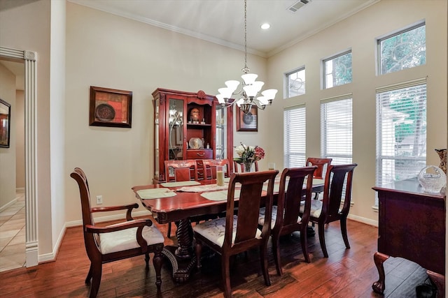 dining area featuring a towering ceiling, an inviting chandelier, ornamental molding, and dark hardwood / wood-style flooring