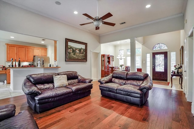 living room with light hardwood / wood-style flooring, ornamental molding, and ceiling fan with notable chandelier