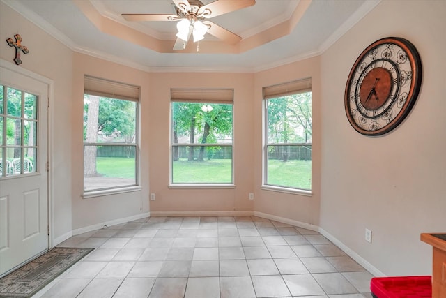 interior space featuring ornamental molding, ceiling fan, a tray ceiling, and plenty of natural light