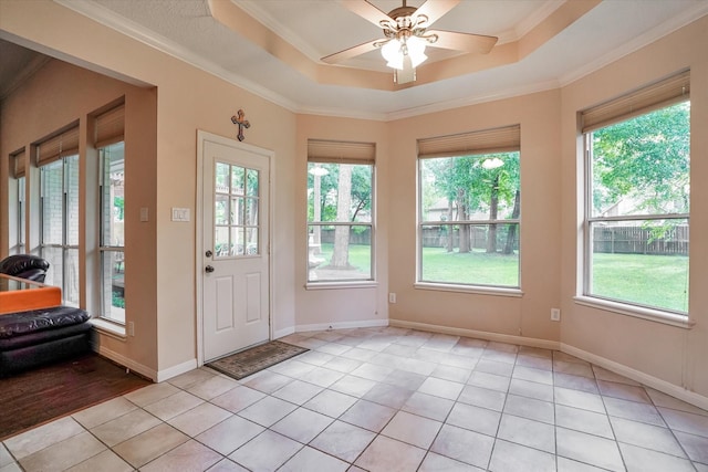 doorway with crown molding, light tile patterned flooring, a tray ceiling, and ceiling fan