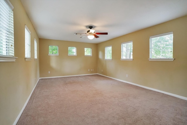 unfurnished room featuring light carpet, ceiling fan, and a wealth of natural light